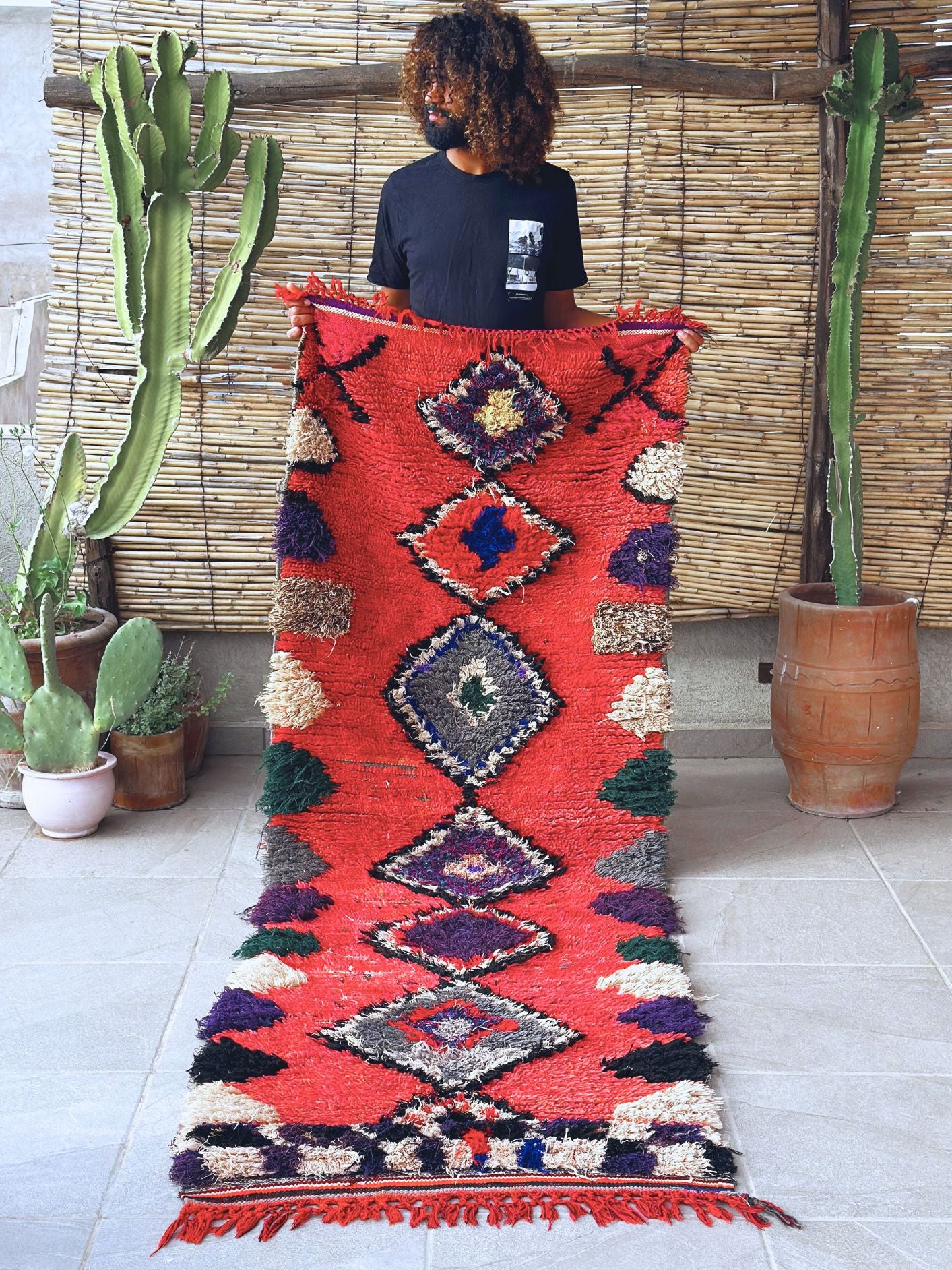 Handwoven Moroccan Boucherouite rug with vibrant geometric diamond motifs, featuring red, violet, green, and cream colors. Crafted by Berber artisans using sustainable recycled materials and wool, ideal for bohemian, eclectic, or modern interiors. Unique cultural design with symbolic motifs from the High Atlas Mountains of Morocco