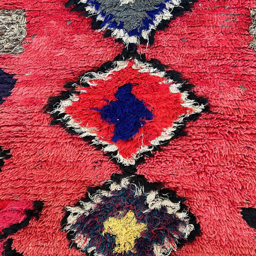 Handwoven Moroccan Boucherouite rug with vibrant geometric diamond motifs, featuring red, violet, green, and cream colors. Crafted by Berber artisans using sustainable recycled materials and wool, ideal for bohemian, eclectic, or modern interiors. Unique cultural design with symbolic motifs from the High Atlas Mountains of Morocco. Photos shows close up diamond motifs and wool texture. 