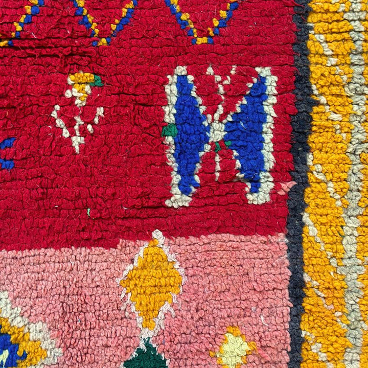 This handwoven Moroccan runner rug with bold red, yellow, and pink hues, featuring geometric Berber motifs is Perfect for boho, modern, contemporary or eclectic interiors. The motifs include diamond (symbolizing protection), zig zag mountain lines, and hourglass shaped butterflies