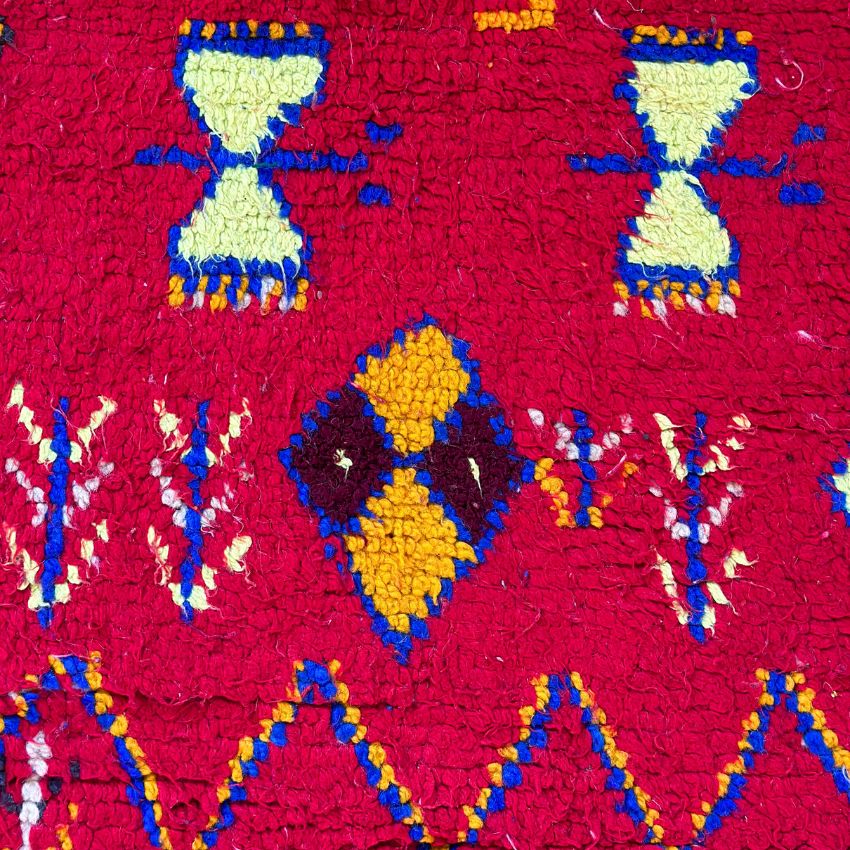 This handwoven Moroccan runner rug with bold red, yellow, and pink hues, featuring geometric Berber motifs is Perfect for boho, modern, contemporary or eclectic interiors. The motifs include diamond (symbolizing protection), zig zag mountain lines, and hourglass shaped butterflies