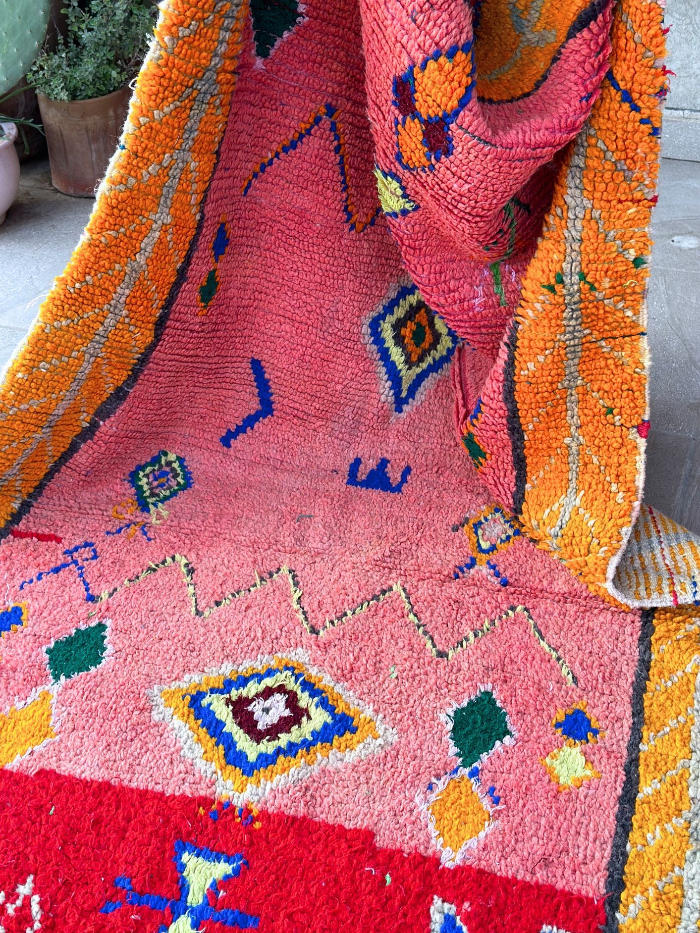 This handwoven Moroccan runner rug with bold red, yellow, and pink hues, featuring geometric Berber motifs is Perfect for boho, modern, contemporary or eclectic interiors. The motifs include diamond (symbolizing protection), zig zag mountain lines, and hourglass shaped butterflies.